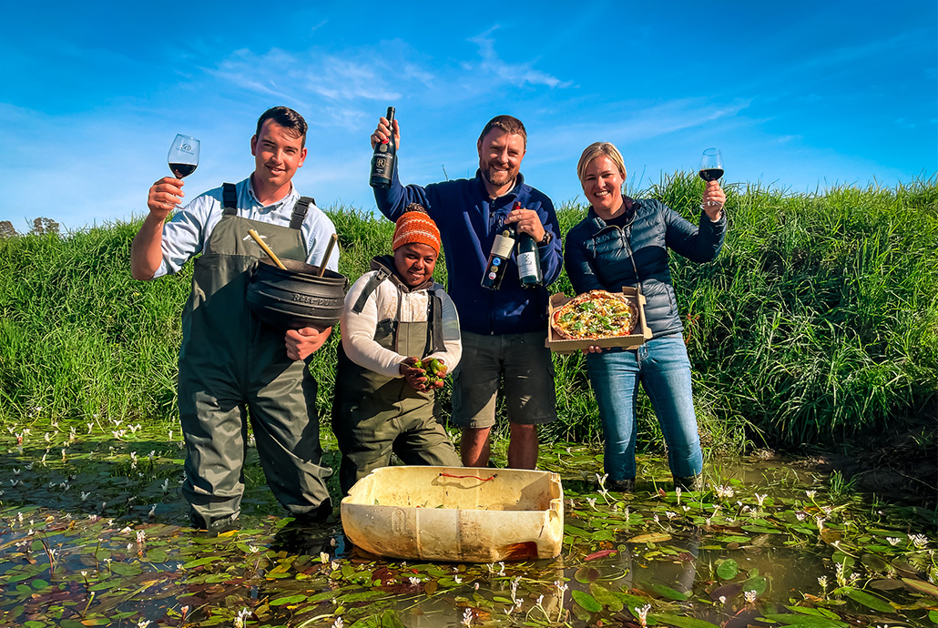 three wine makers from the paarl wine region standing in a small pond filled with waterblommetjies that are used in food.