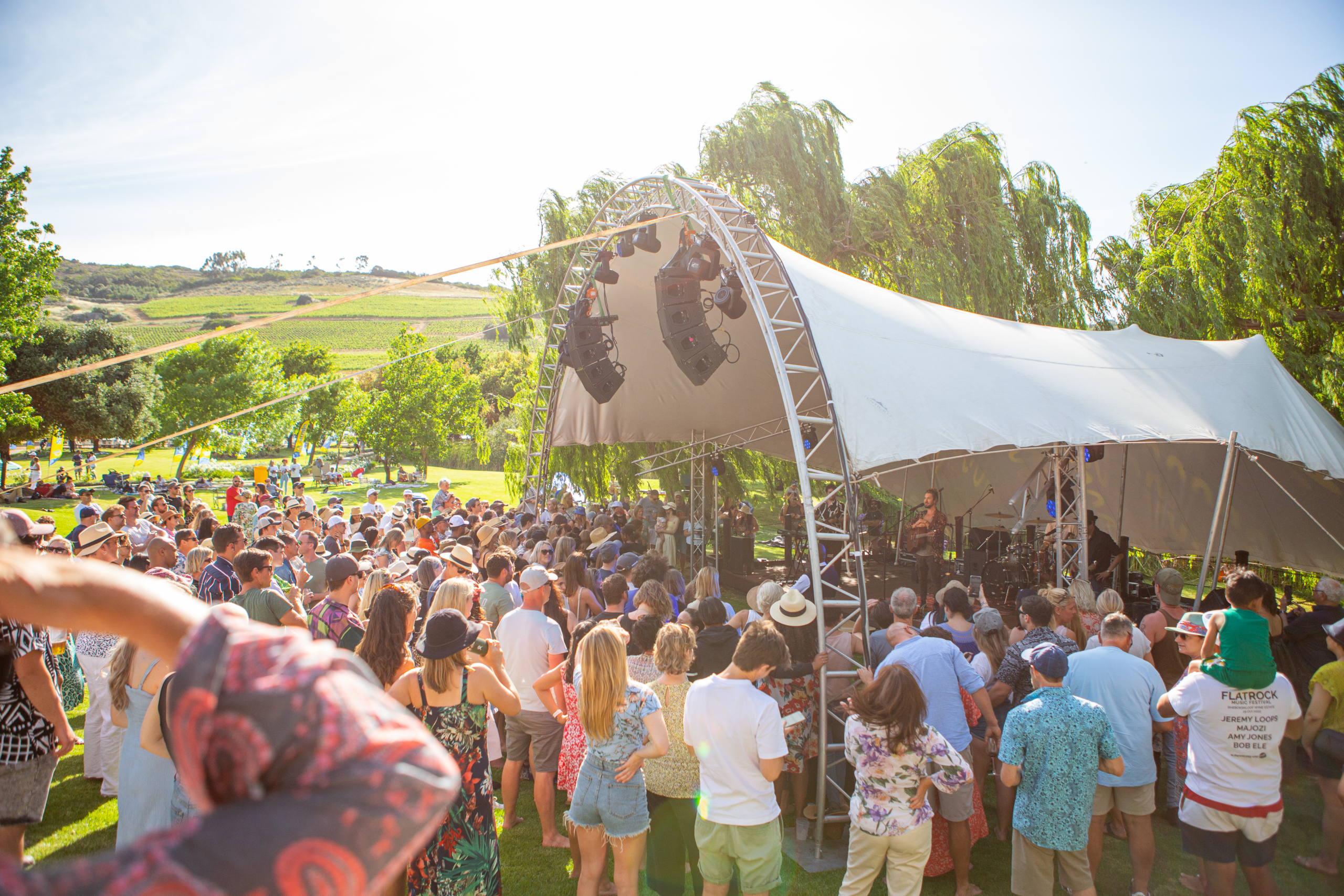 a crowd of people gathered at the stage ion a summer afternoon at a one of the biggest music events outside of cape town on a wine estate in Paarl