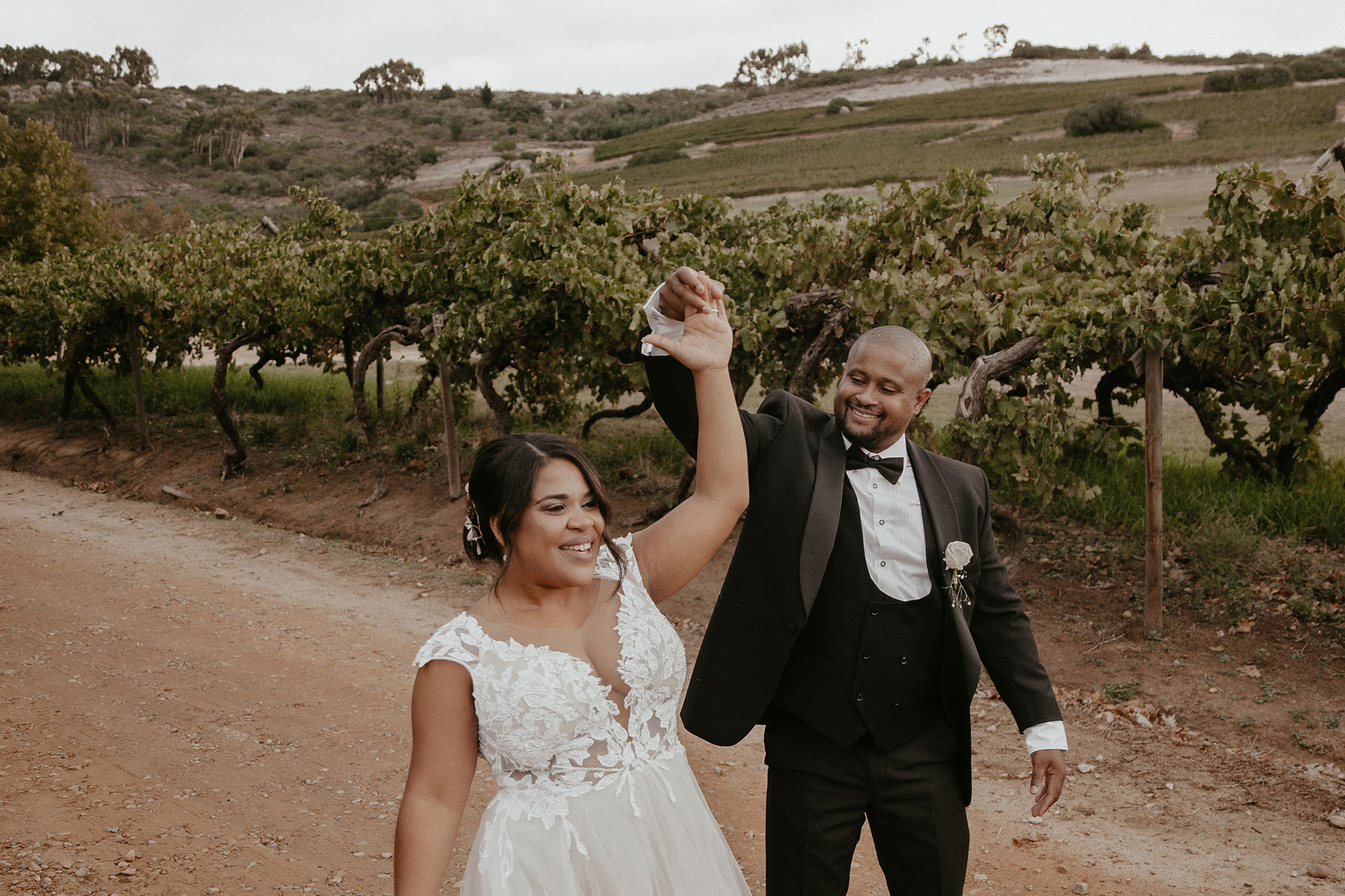 A groom lovingly turns his bride around amongst the vineyards at Rhebokskloof which has one of the best wedding venues in Paarl.