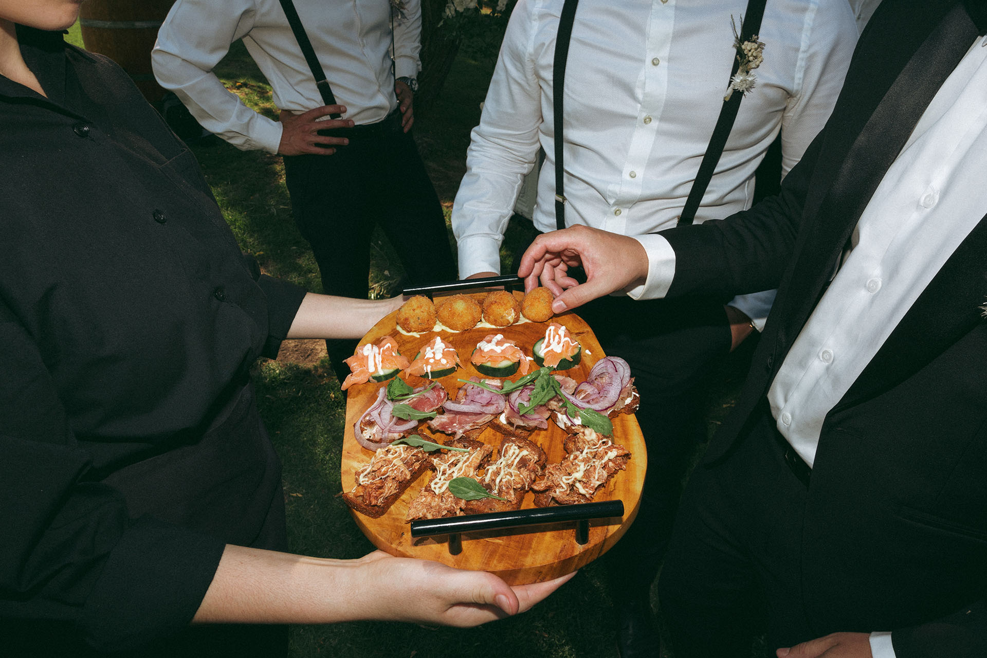 a guest carefully picks off a bitterballen canape of the chacuterie board at one of the best garden wedding venues in the Cape winelands.