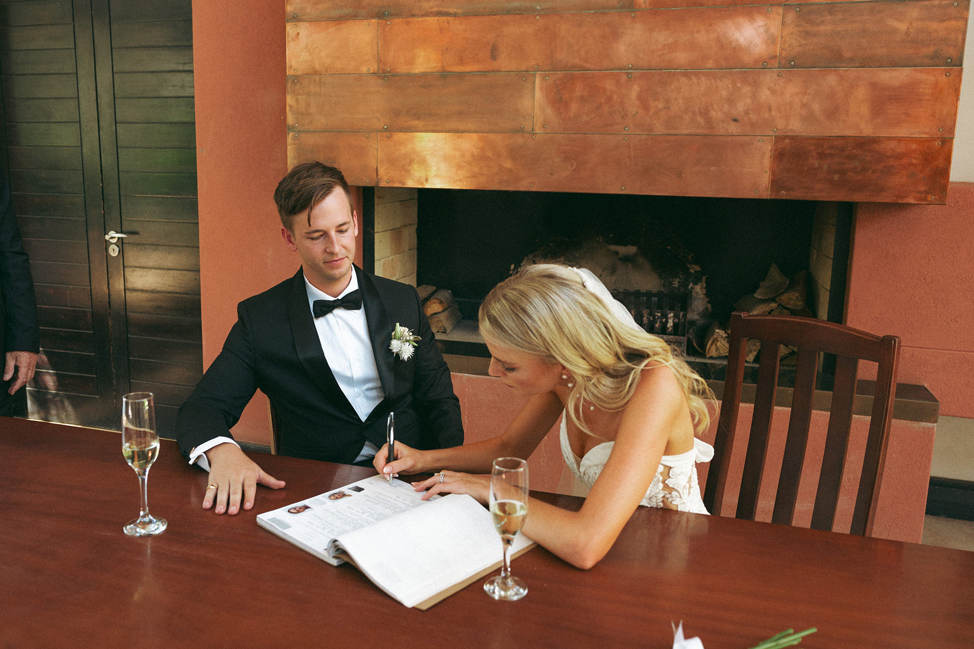 Newlyweds sign the wedding registry together while sipping champagne at Rhebokskloof estate's which offer an array of perfect summer garden wedding venues.