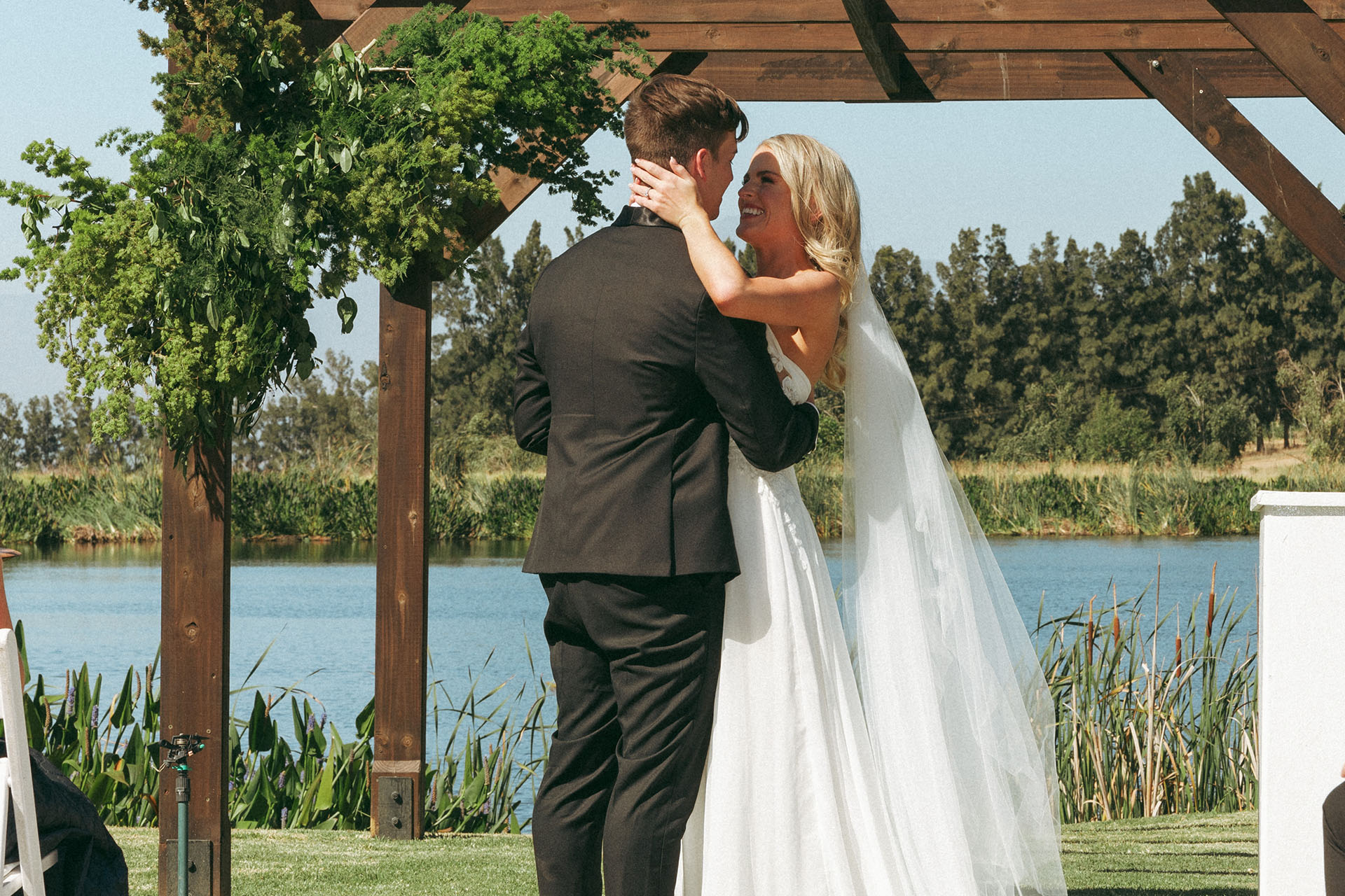 a bride and groom who got married in one of the most stunning garden wedding venues in South Africa look at each other lovingly at the alter by the lake.