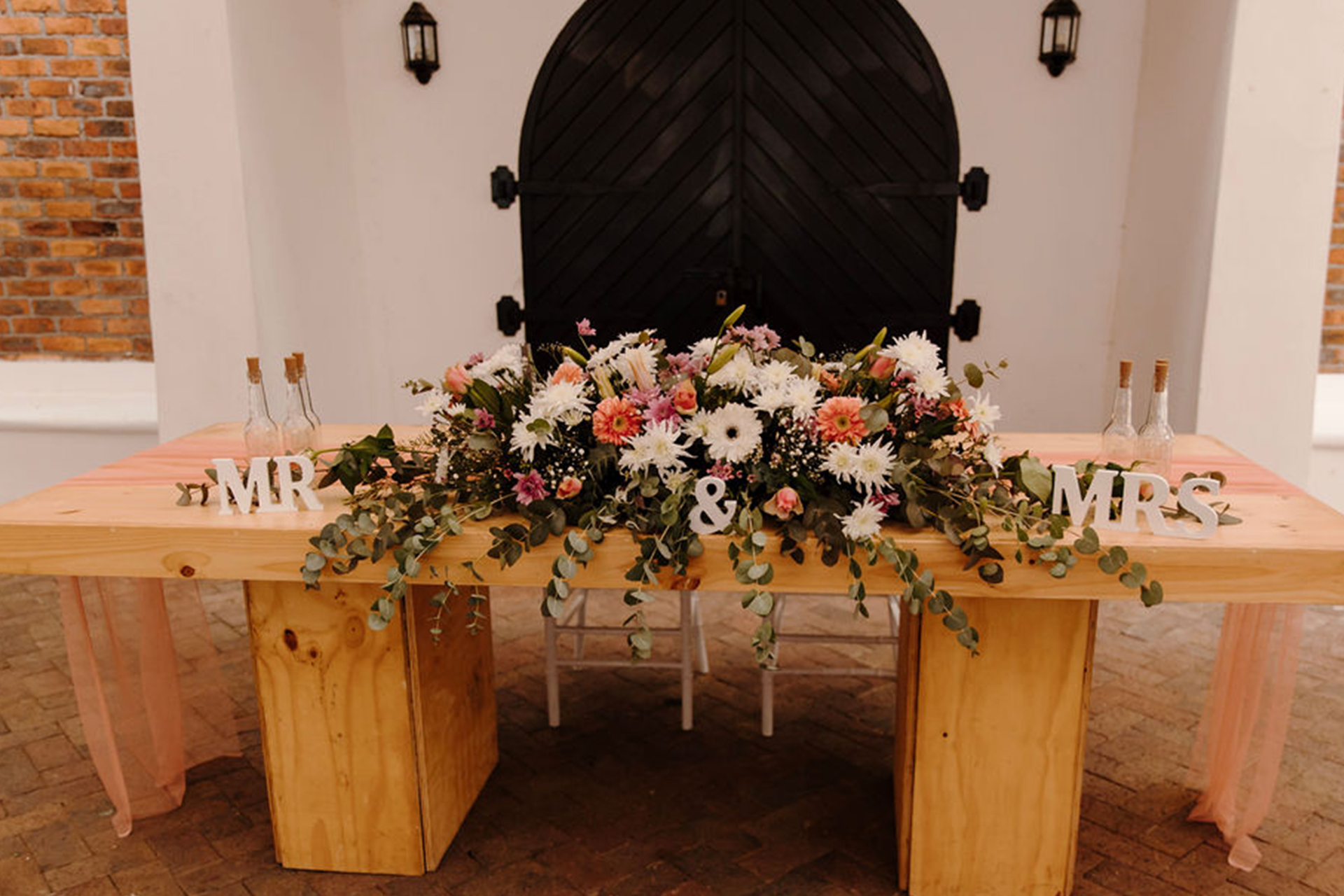 the main wedding table at the winter wedding reception venues at Rhebokskloof estate that is overflowing with colourful flowers.