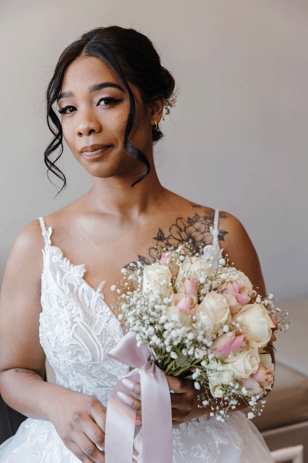 a beautiful bride looks at the camera posing with a soft pastel bouquet of flowers she wore at one of the best winter wedding venues in the western cape.