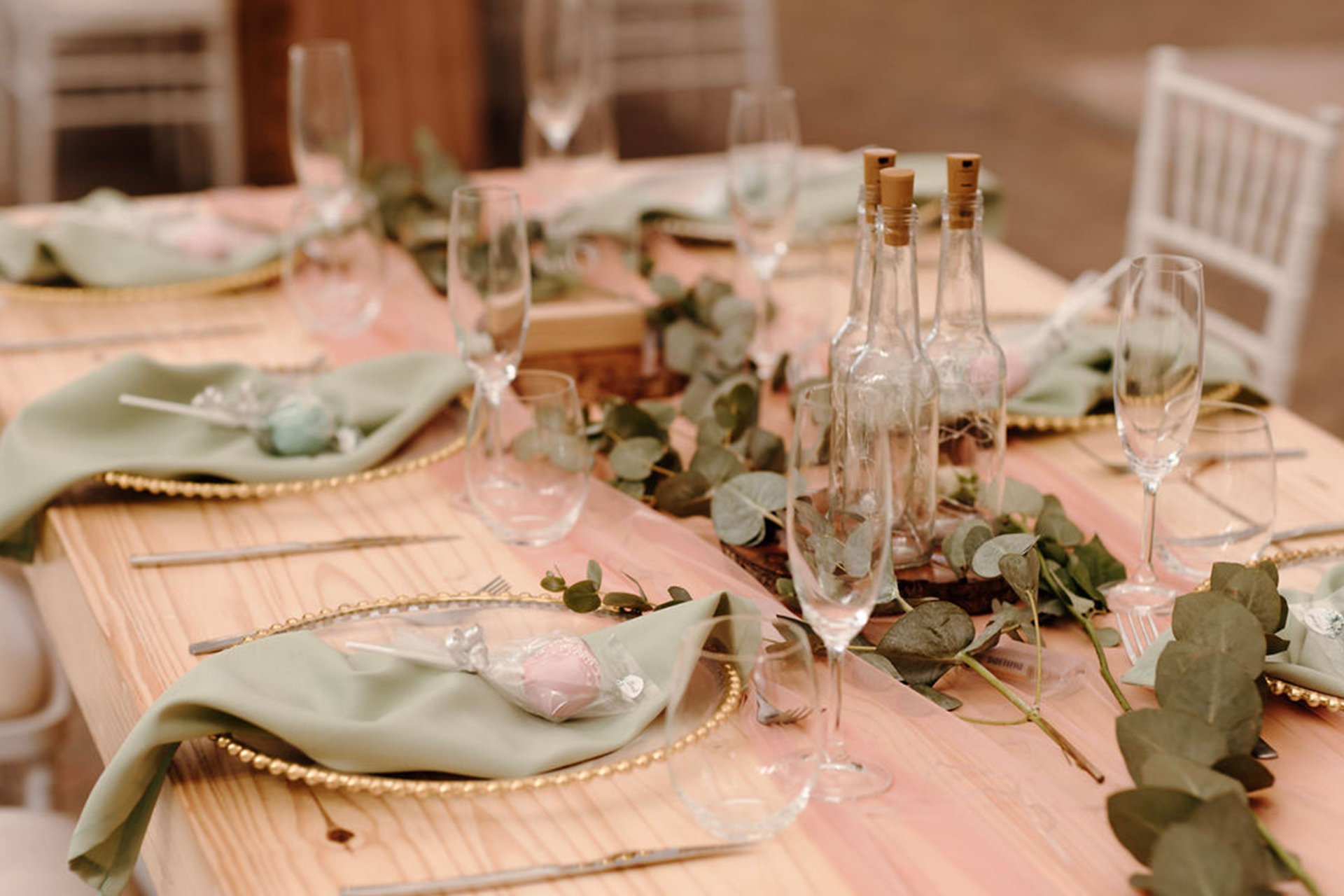 winter wedding venue details in pastel green and pink with earthy green succulent foliage arranged around gold rimmed plates.