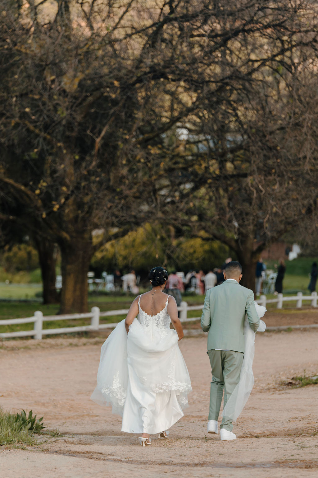 a stunning moment as the bride walks from her photoshoot holding up her dress and her husband holds her veil in a winter landscape.