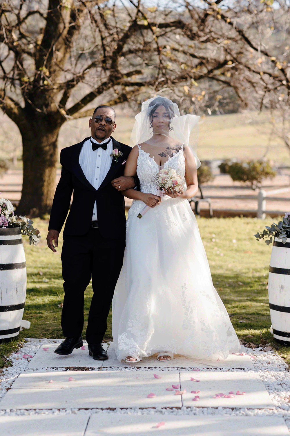 A winter bride from Cape Town walks down the aisle with her father in outdoor ceremony in August at Rhebokskloof Estate in Paarl.