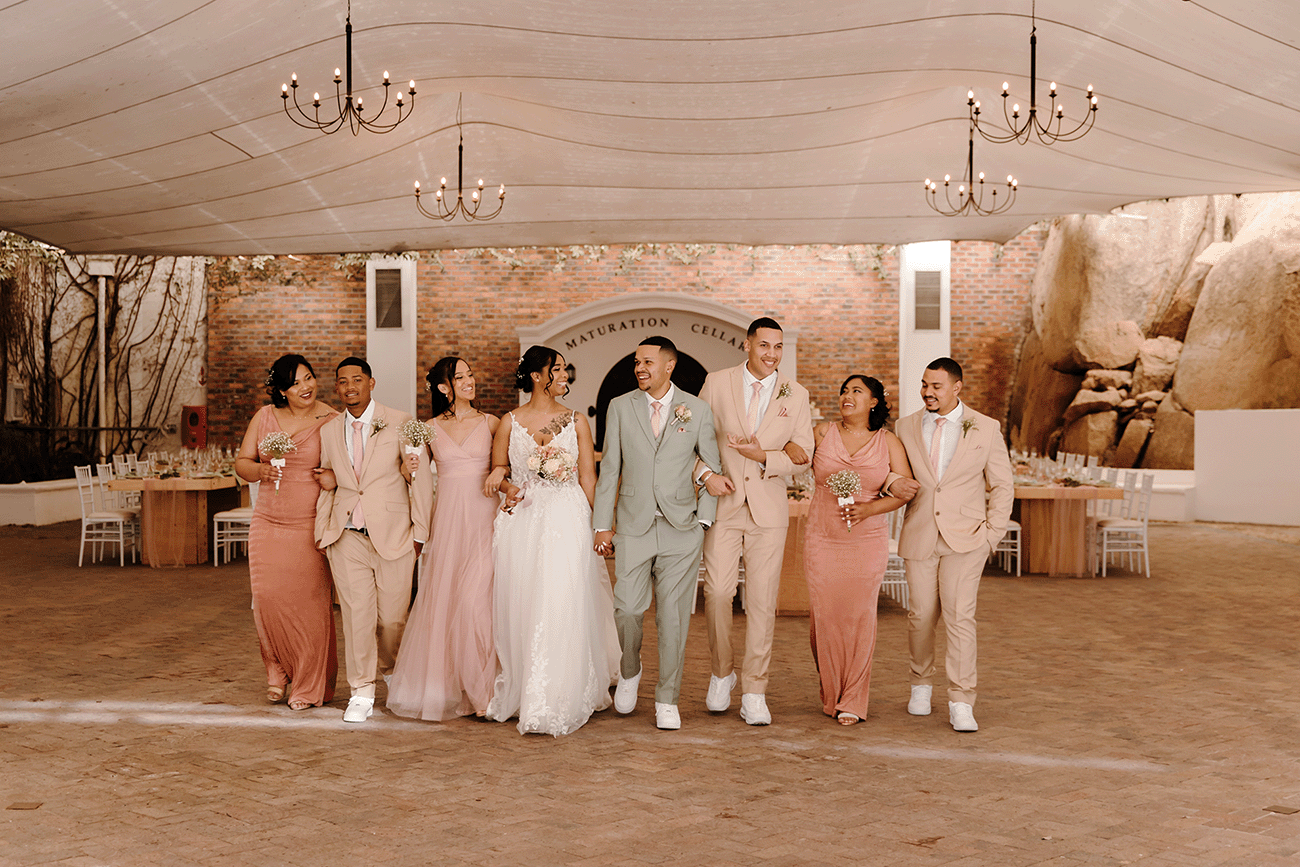 a stunning young bridal party in pastel shade clothing walk in the popular Rhebok function venues at Rhebokskloof estate for a wedding.